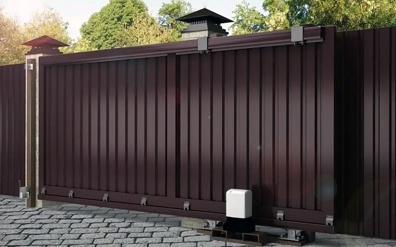 A modern sliding metal fence with automatic opening system, installed on a cobblestone path