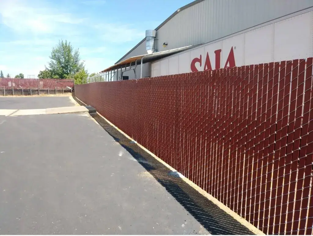 A red chain-link fence with privacy slats, enclosing a commercial property area.