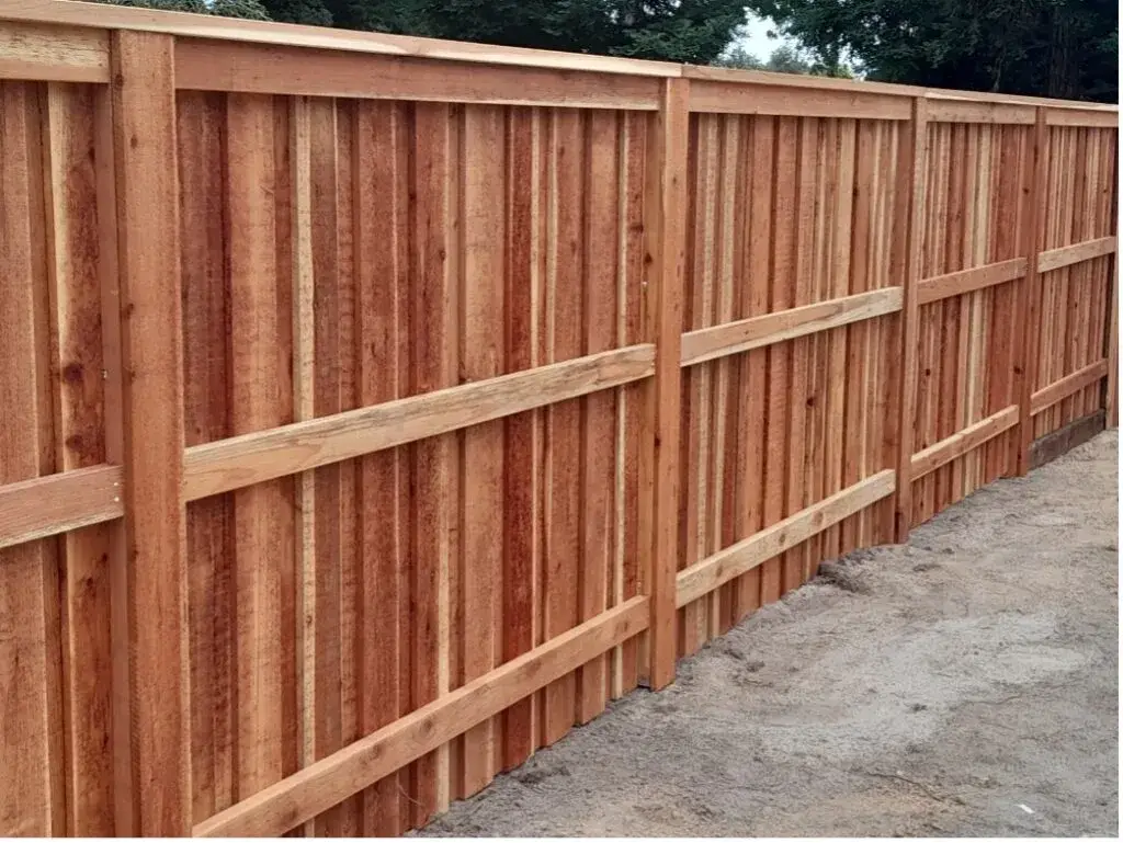 A sturdy wooden privacy fence with vertical slats and horizontal reinforcements.