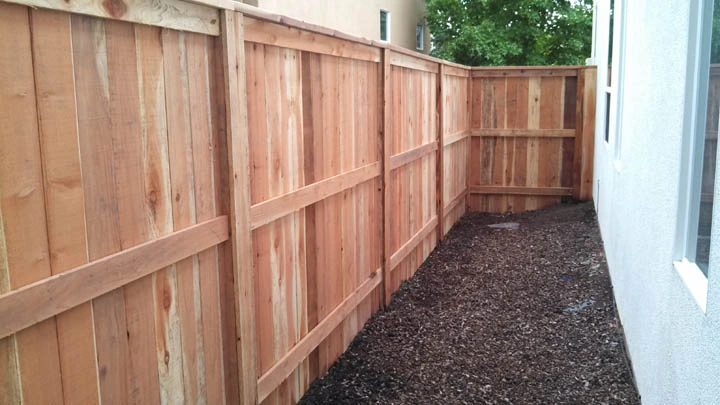 A clean, well-maintained wooden fence on a property boundary, showcasing the Fence Law in practice.